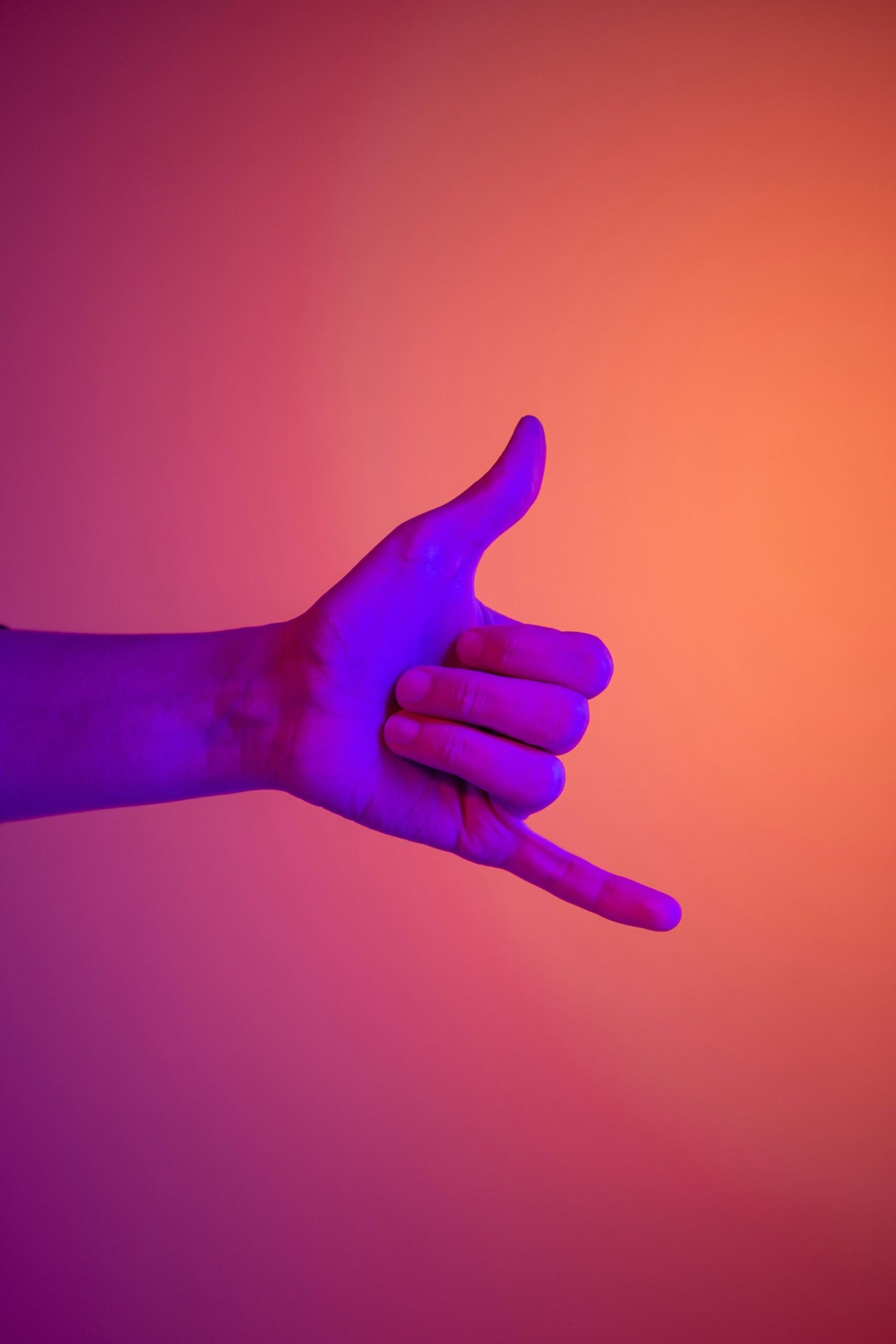 A radiant hand gesture in neon colors, symbolizing communication and friendship on a vibrant orange background.